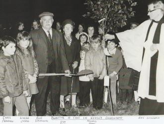 Kersey School Centenary 1973, planting a tree in Kersey churchyard.  At front of picture:  Chris Partridge, Linday Orriss, Bob Spraggons, Eva, Michael Pryke and Rev. Goddard. 